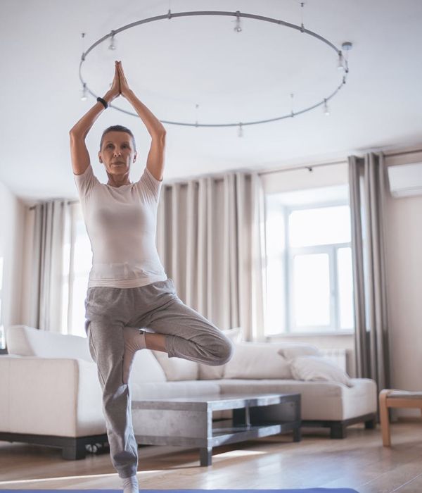 Woman in a calming yoga pose in a bright room.